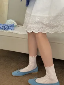 Close-up detail of women sweet pink striped socks paired with blue flat shoes and white skirt.