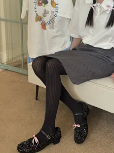 Close-up detail of women's black vertical striped tights styled with sequin shoes.