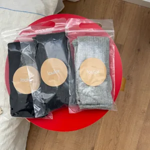 Detail shot of ribbed tights in three colors, packed in clear bags with brand label.