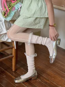 Detailed view of sweet lace tights and ruffled slouch socks paired with silver flats.