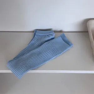 Close-up detail of light blue ribbed stirrup leg warmers, soft knit texture, casual everyday wear.
