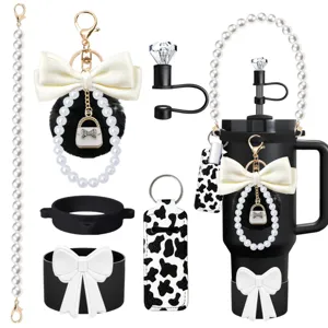 Close-up detail of tumbler accessories set featuring pearl strap, pompom and cow print.
