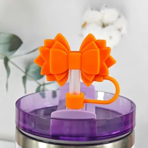 Silicone bow straw cover detail shot, dust plug accessory for tumbler cups, vibrant orange design.