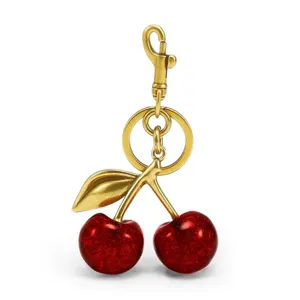 Gold-tone cherry keychain and bag charm featuring glittery red fruit and a metal leaf clip.