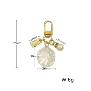Gold keychain detail with pearl shell pendant and size dimensions specification display.