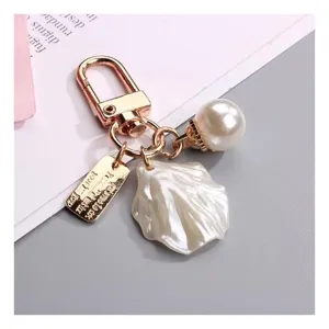 Gold keychain with pearl shell and round pearl pendants, stylish handbag charm and accessory.