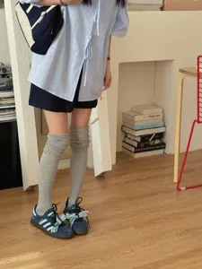 Close-up detail of grey over-the-knee stack socks worn with casual outfit and sneakers.