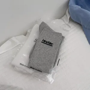 Close-up detail shot of packaged grey and white stackable long socks in transparent bags.