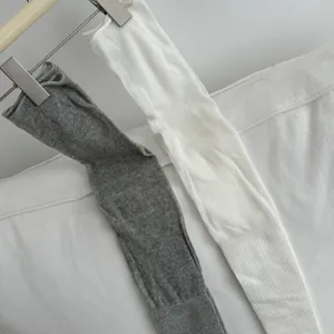 Detail shot of solid color over-the-knee long socks in gray and white with rib cuff design.