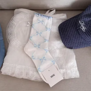 Detailed view of sweet Japanese style white socks featuring blue bow pattern and lace ruffle cuff.