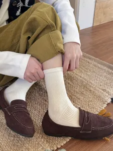 Close-up detail shot of white ribbed mid-calf socks worn with classic brown shoes.