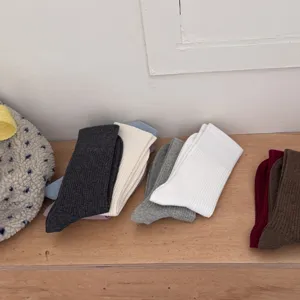 Detail view of solid color ribbed long socks in various colors displayed neatly on shelf.