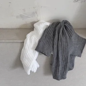 Close-up detail of soft knitted ribbed leg warmers, showing texture and dual-color display.