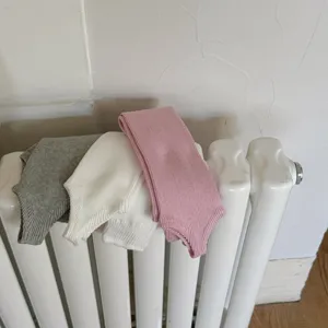 Dettaglio scaldamuscoli con staffa in maglia grigia, bianca e rosa, calze accoglienti.