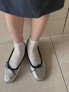 Detail shot of women's white short socks featuring black polka dots and delicate lace trim.