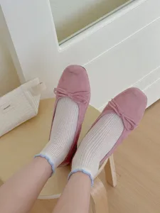 Detaillierte Nahaufnahme trendiger rosa Ballerinas kombiniert mit süßen weißen Socken.