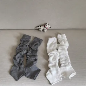 Detailed view of ribbed slouch stirrup leg warmers in grey and white, showcasing knit texture.