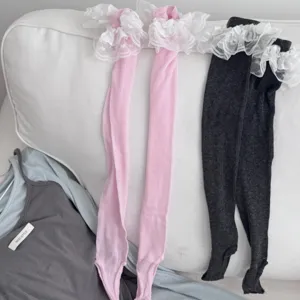Detailed shot of women stirrup socks with delicate white lace trim in pink and dark grey colors.