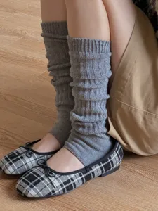 Close-up detail shot of gray knit stirrup leg warmers featuring vertical ribs and soft texture.