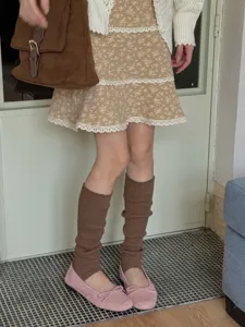 Scaldamuscoli marroni con staffa abbinati a scarpe Mary Jane rosa per uno stile accogliente.