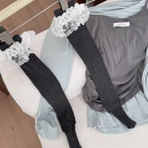 Dark grey stirrup socks detail, featuring delicate white lace ruffles for daily wear.
