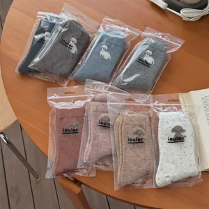 Detailed close-up shot of cute wool speckled socks in transparent packaging, cozy winter daily wear.