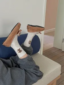Cozy detail shot featuring cute pattern mid-calf socks and warm suede footwear indoors.
