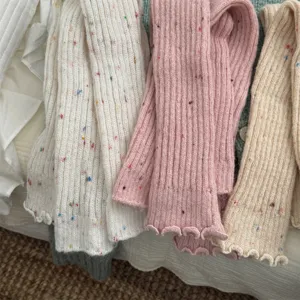 Primo piano dettagliato di scaldamuscoli in morbida maglia con pois colorati invernali.