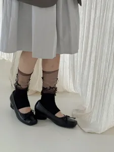 Gedetailleerd overzicht van mesh strik stijgbeugelsokken, elegante zwarte beenwarmers voor outfits.
