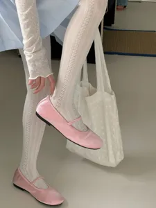 Gedetailleerde close-up van elegante witte panty's met motief en stijlvolle schoenen.