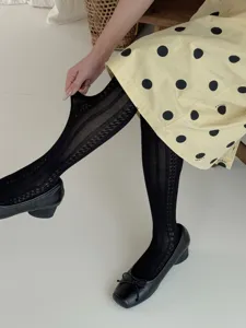Gedetailleerd overzicht van elegante zwarte transparante panty's met patronen en platte schoenen.
