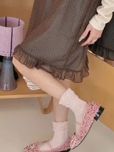 Nahaufnahme von transparenten Damen Rüschen Kurzsocken kombiniert mit Pailletten Schuhen.