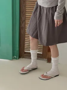 Detailed shot of white ruffled calf socks and leg warmers styled with skirt for spring.