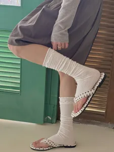 Detail shot of white ruffle leg warmers socks with delicate ribbed trim and comfortable fit.