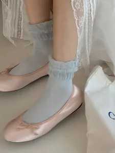 Detailaufnahme einfarbiger Rüschenbündchen-Socken und Seiden-Ballerinas, weich und süß.
