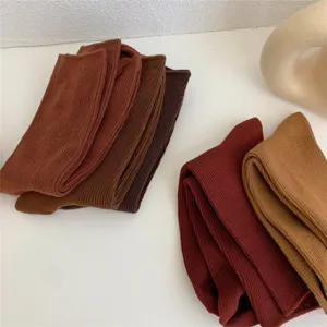 Nahaufnahme von einfarbigen Baumwollsocken in warmen Erdtönen, weiche feine Strickstruktur.
