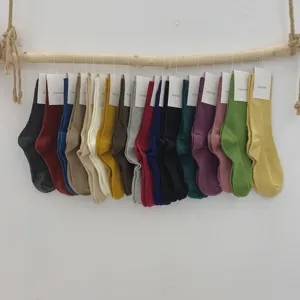 Vue détaillée de chaussettes empilées en coton uni mi-tubulaires suspendues sur une branche.