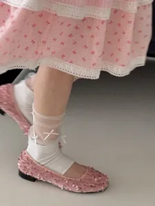 Detail van schattige sokken met strikjes en roze pailletten schoenen voor zoete stijl.
