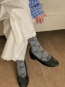 Grey mid-calf socks featuring a cute black bow pattern, perfect for sweet everyday styling.