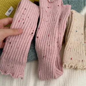 Vista dettagliata di scaldamuscoli spessi in cashmere maculato, morbido design a coste.