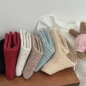 Detailed shot of thick speckled knit crew socks in assorted cozy colors on wooden shelf.