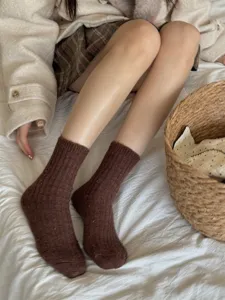 Detail shot of thick wool blend winter crew socks with colorful specks, worn on bed.
