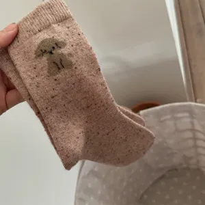 Cute puppy patterned wool speckled knit mid-tube socks detail view, soft autumn winter wear.