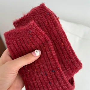 Close-up detail of thick red knit wool crew socks with colorful nep yarn texture.