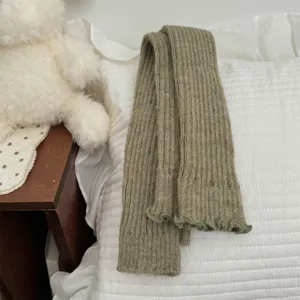Primo piano di scaldamuscoli in maglia con punti colorati su cuscino bianco, dettaglio accogliente.