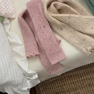 Primo piano di scaldamuscoli in maglia accogliente con consistenza morbida e pois colorati.