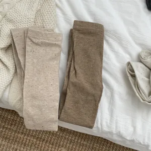 Detailed shot of soft cotton flecked tights in neutral beige and brown tones, cozy style.