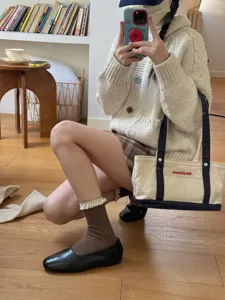 Gros plan de chaussettes mi-mollet en dentelle douce associées à un gilet en maille.