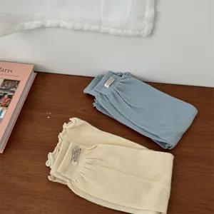 Detailed view of solid color knit leg warmers in blue and cream, styled neatly on a wooden table.