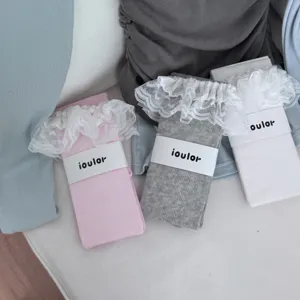 Detail shot of cute lace ruffle socks in pink grey and white with paper band packaging design.